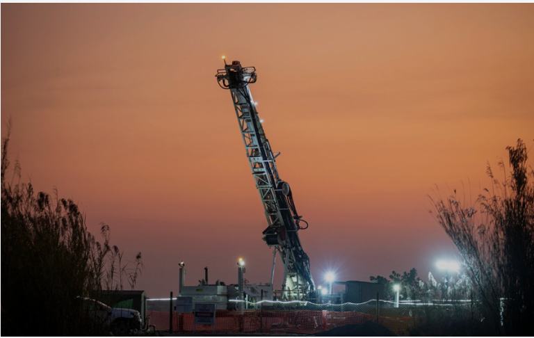 Illuminated drill rig at dusk on a deep hole programme